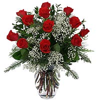 One dozen long stem red roses are arranged with delicate white baby's breath in ...
