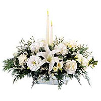 White flowers with 2 white taper candles and holid...