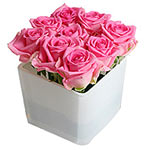 Six exquisite roses are artistically arranged in a clear cube vase to create a s...