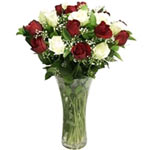 A vase of red and white roses surrounded with delicate baby?s breath and greener...