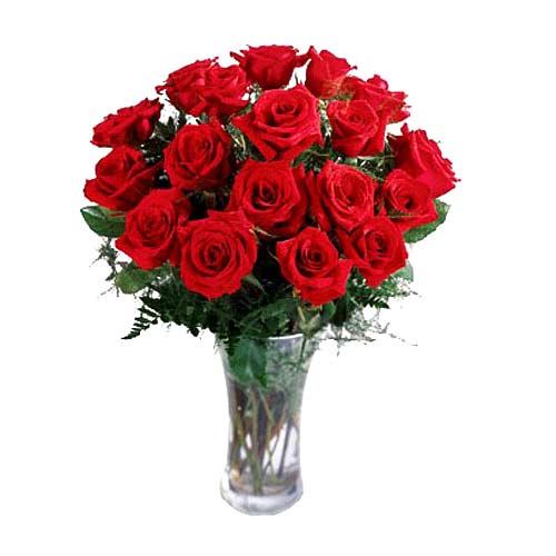 18 Roses artfully arranged in a glass vase with greens